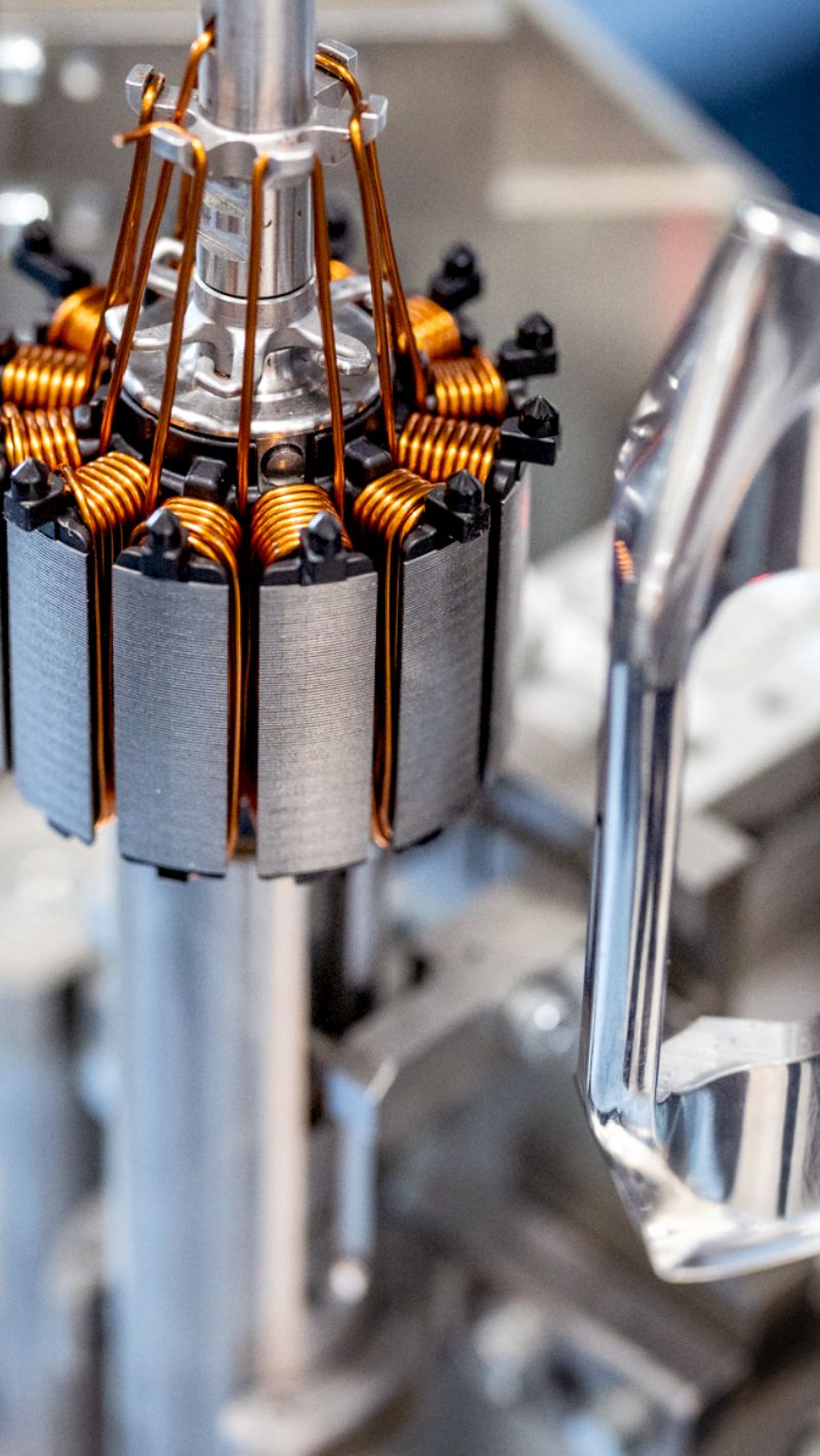 Offene Rotorbaugruppe mit Kupferwicklungen h&auml;ngt an Montagevorrichtung und zeigt Details der Elektromotorfertigung